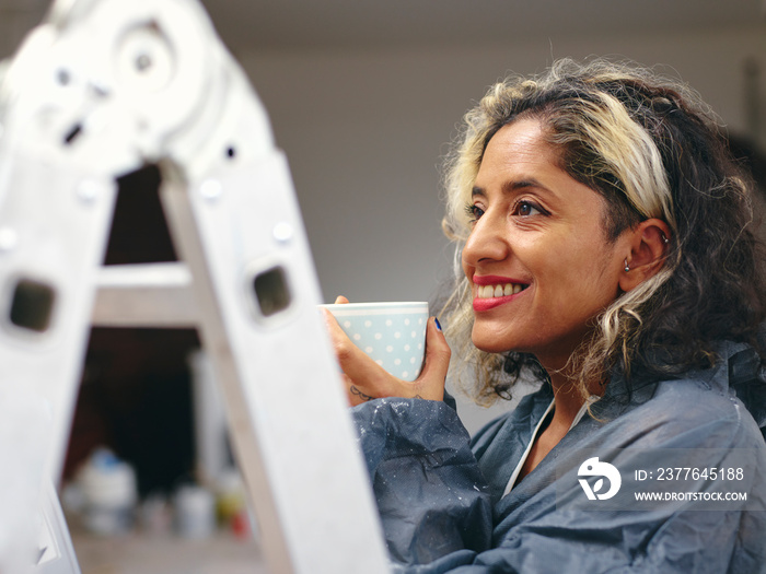 Smiling woman having coffee break during renovation