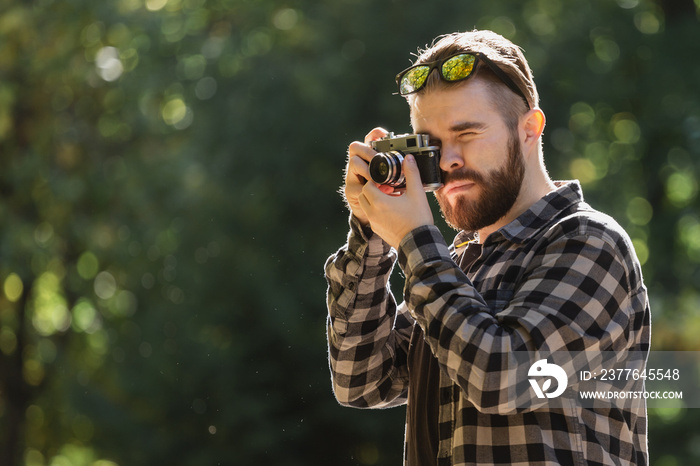 Portrait man photographer taking picture with vintage camera on city green park copy space and place for text - leisure activity and hobby concept