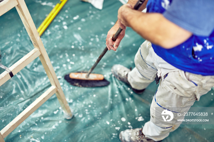 Worker using broom for cleaning dirt during renovaton of the house.