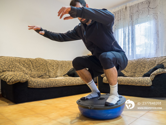 Athlete doing strength and balance exercises on a bosu ball at home.