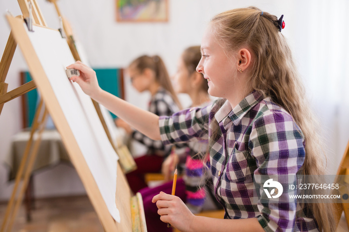 children draw on an easel in art school.