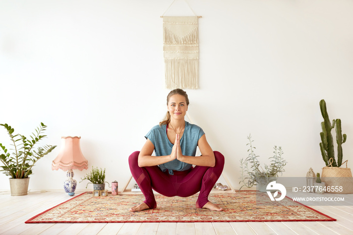 fitness, people and healthy lifestyle concept - young woman doing garland pose at yoga studio