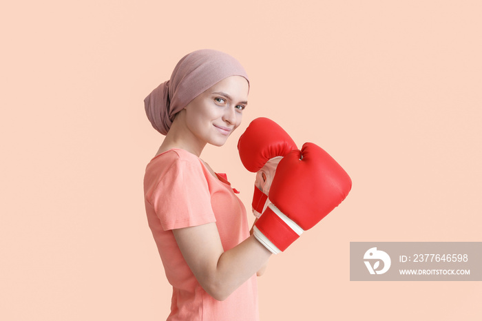 Woman after chemotherapy in boxing gloves on color background. Fight against cancer