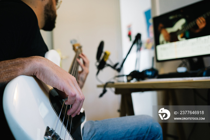 man learning how to play the bass doing an online class from home