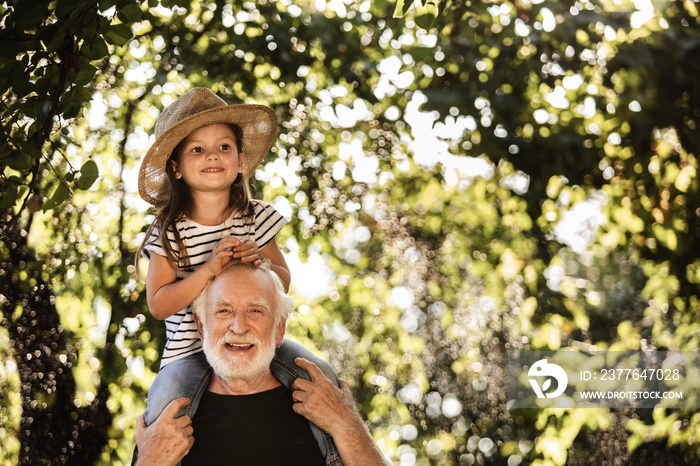 Little girl with old man having fun in garden