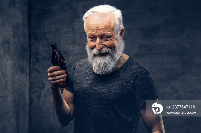 Studio shot of glad grandfather dressed in shirt with modern hairstyle against dark background.