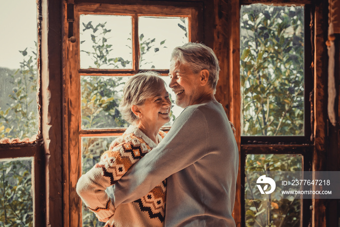 Happiness and togetherness concept lifestyle with senior retired caucasian couple enjoy love and relationship at home hugging and laughing. Man and woman elderly life concept indoor