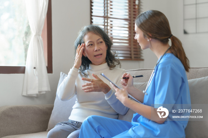 Portrait of attractive young caucasian female nurse elderly caregivers with senior patient home caring for elderly asia female patients on couch, indoors.