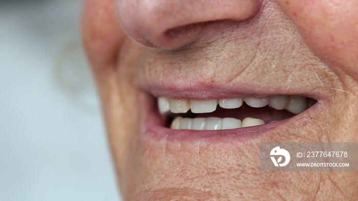 Closeup mouth of elderly woman talking and smiling with perfect teeth