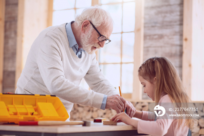 Interesting occupation. Smart nice man doing a drawing while helping his granddaughter