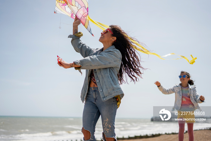 Mother and daughter (8-9) flying kite on beach
