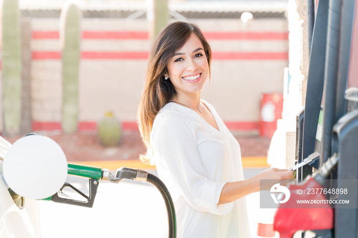 Female Customer Using Fuel Pump At Gas Station