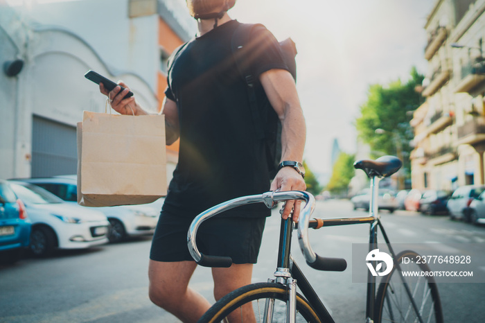 Man courier using a map app on mobile phone to find the delivery address in the city. Anonimous Courier delivery food service at home