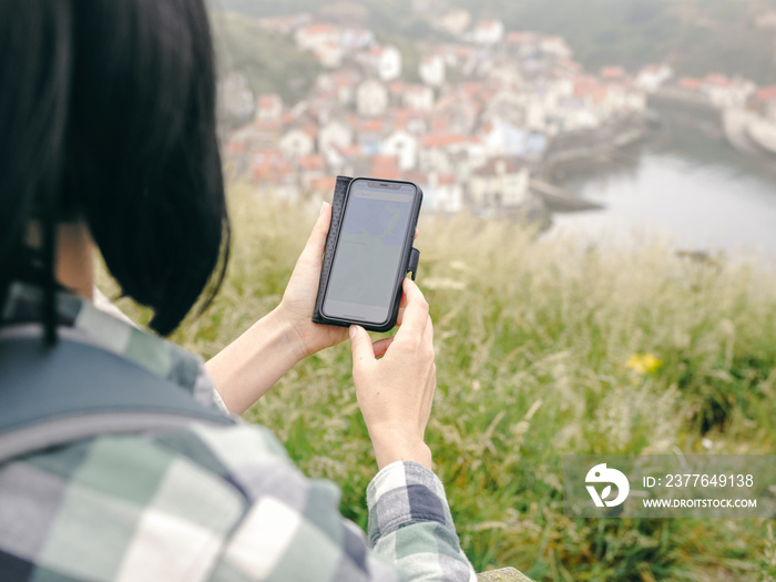 UK, Close-up of female hiker looking at map on smart phone inÊlandscape