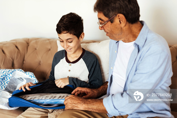 Elderly smiling grandfather giving birthday present to his grandson. Grandpa presents his grandson with a musical instrument.