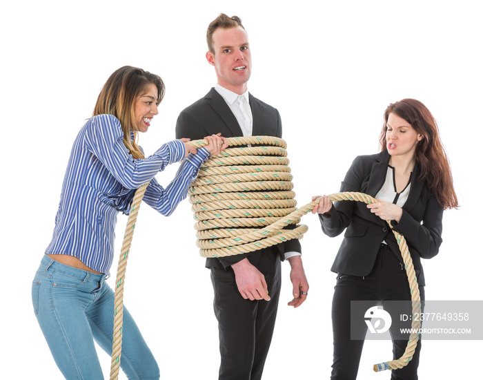 Two angry woman tying a business man with rope