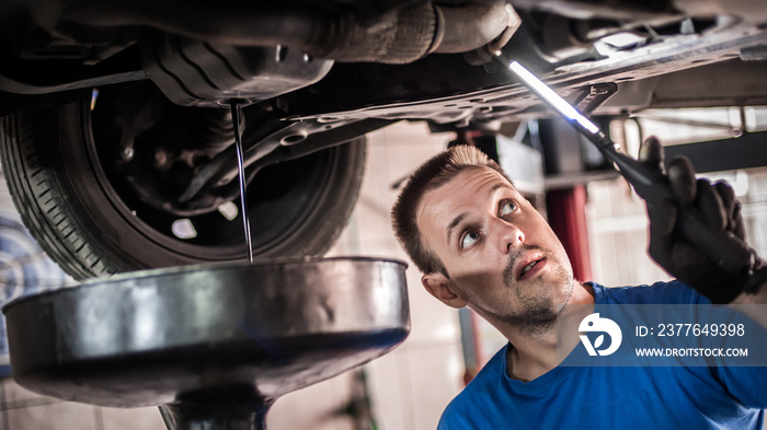 Mechanic discharges motor oil from engine tank under the car