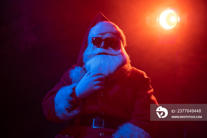 Santa claus in sunglasses in neon light on a black background. Christmas party.