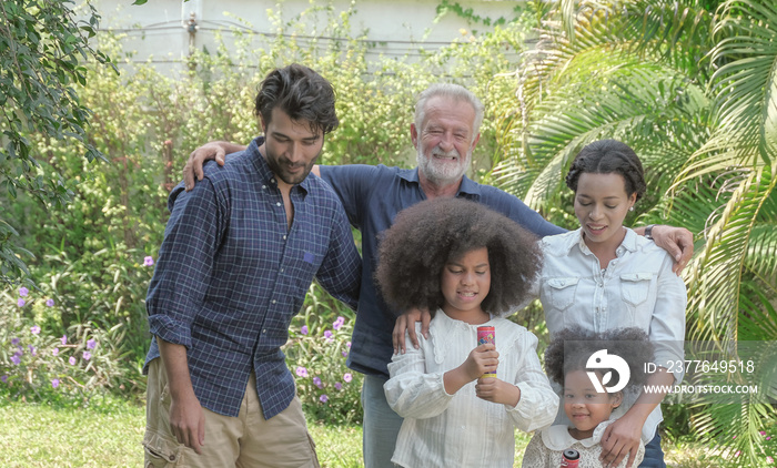 Multi ethnic caucasian - african family group relax taking a walk and prepare for celebration together on holiday at backyard house with happy smiling face. Selective focus.