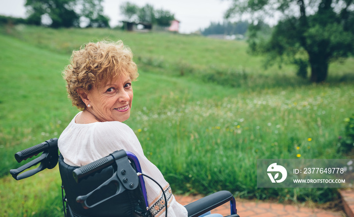 Smiling senior woman in wheelchair in the garden