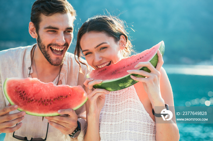 Cheerful couple holding slices of watermelon