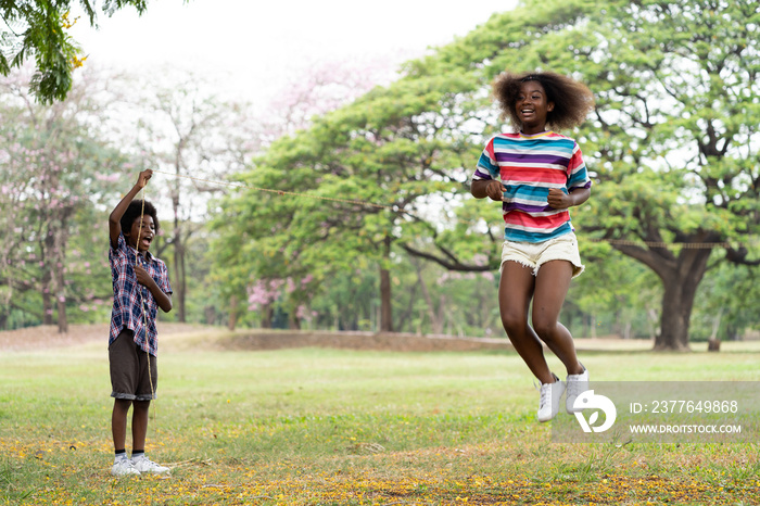 African American girl playing jumping over the rope in the park. Young  girl jumping over the rope outdoor. Education, field trip concept