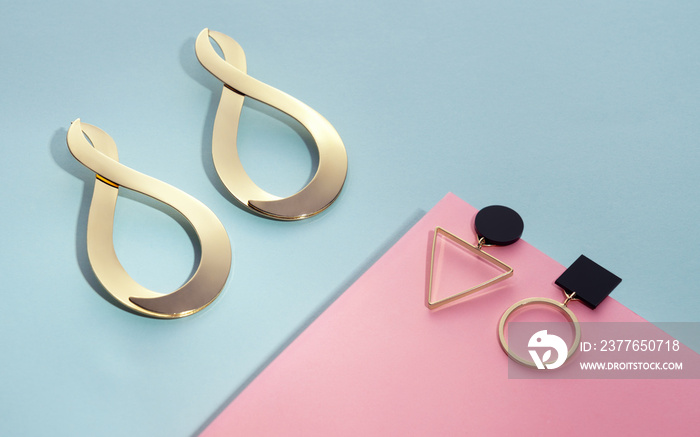 Top view of Geometric shapes golden Earrings on blue and pink background