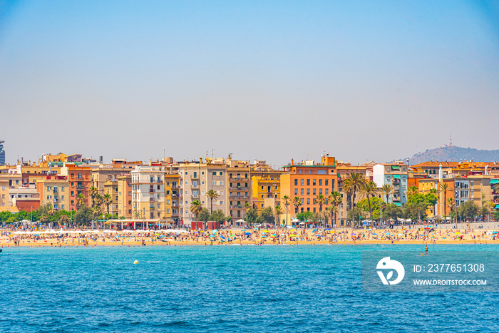 People are enjoying a sunny day on Barceloneta beach in Barcelona, Spain