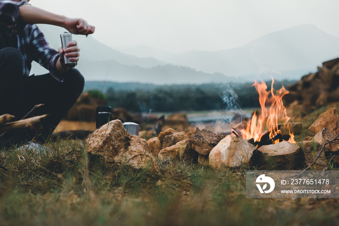 Bonfire in camping of people camper group in nature near the mountains with coffee brewing equipment.