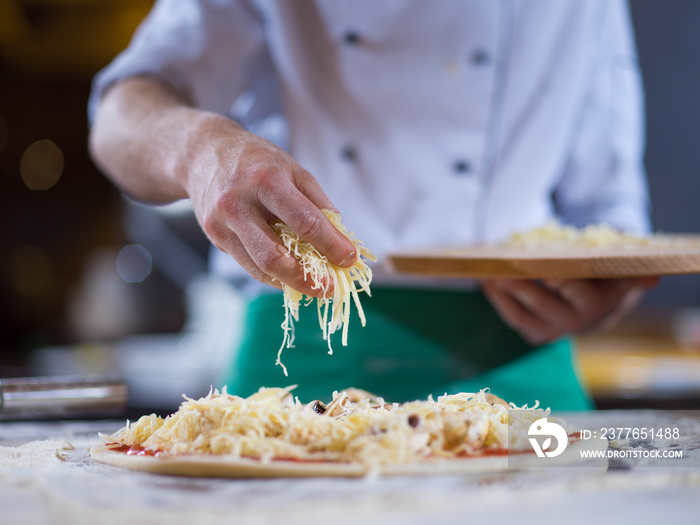 chef sprinkling cheese over fresh pizza dough