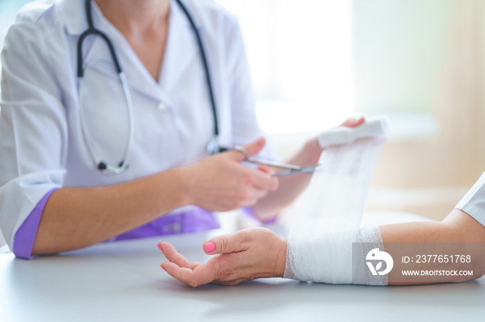 Doctor is bandaging wrist of patient in clinic