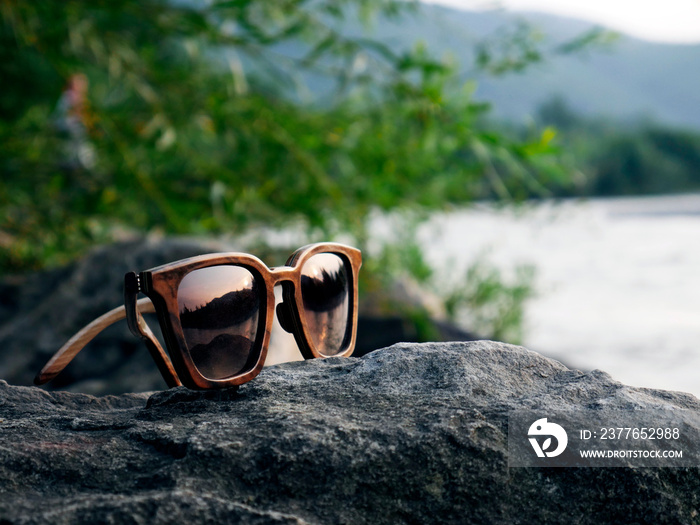 wooden sunglasses at sunset on river with reflection