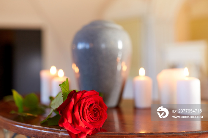 red rose and cremation urn with burning candles