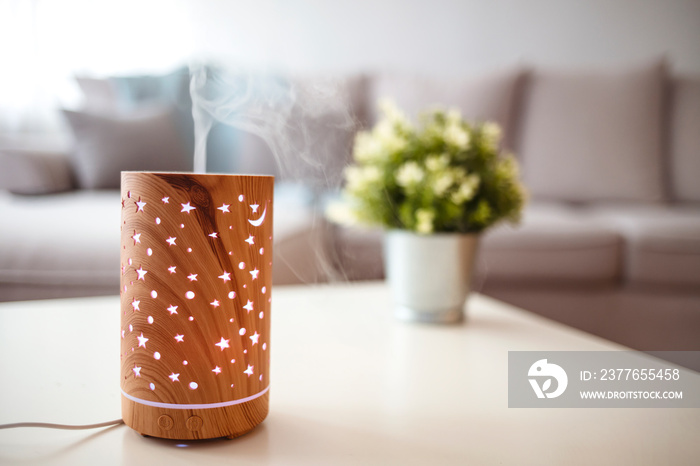 Diffuser spreading essential oils in livingroom and woman relaxing. Aroma health essence, welness aromatherapy home spa fragrance tranquil theraphy, therapeutic steam, mental health treatment