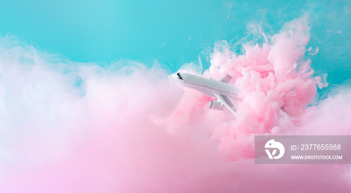 Passenger jet airplane flying through pastel pink clouds. Minimal transportation, travel or vacation concept.