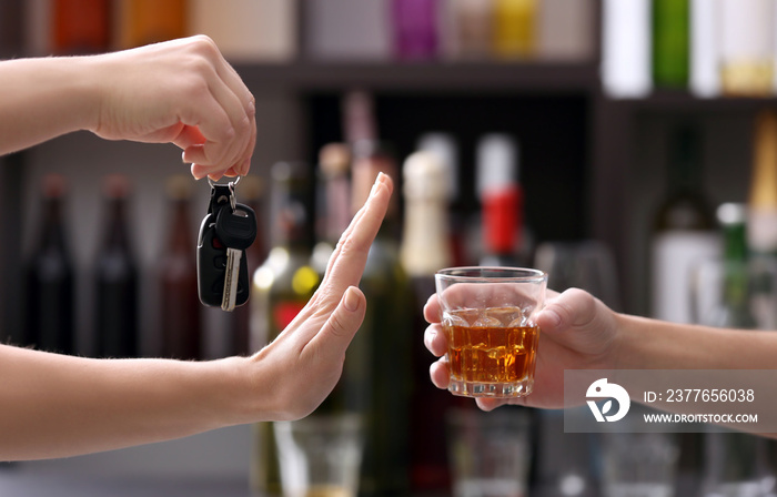 Woman with car key refusing glass of alcoholic beverage, on blurred background. Don’t drink and drive concept