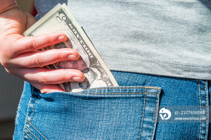 Woman hand putting money in jeans pocket