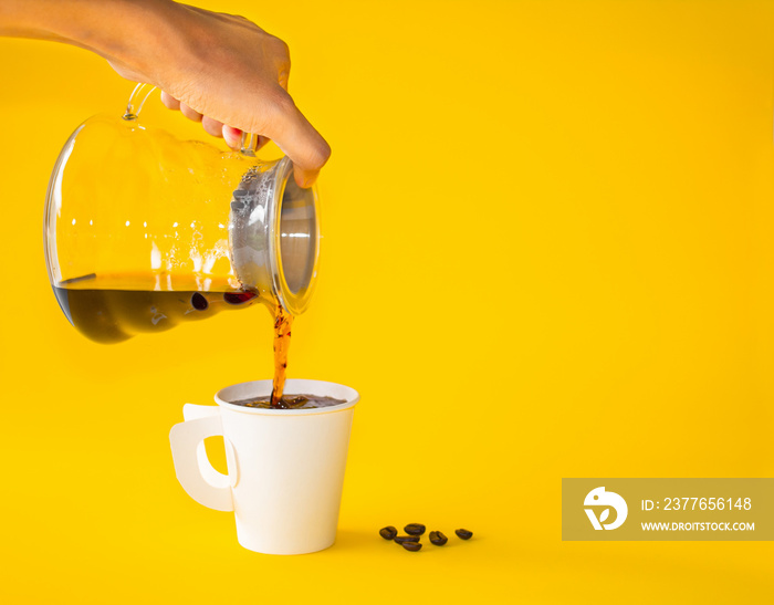 Hand woman pouring coffee on white paper of  cup  on yellow background. Copy space for your text