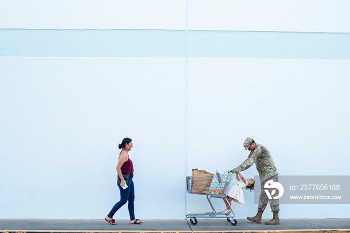 Soldier and his daughter pushing a shopping cart