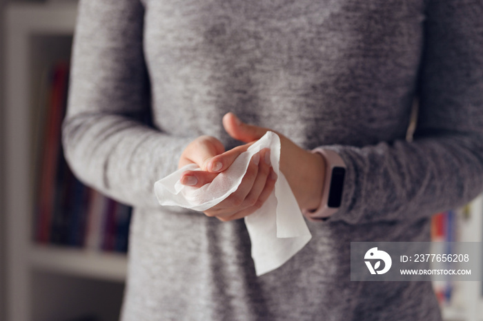 Close up on midsection of young caucasian woman hands wiping using white alcohol tissue cleaning napkin disinfection from virus and bacteria in day at home or office front view