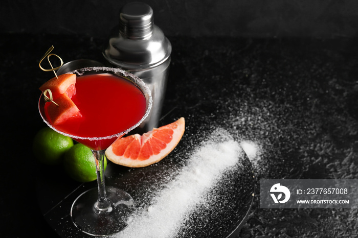 Glass of Hemingway daiquiri cocktail, shaker and citrus fruits on dark background