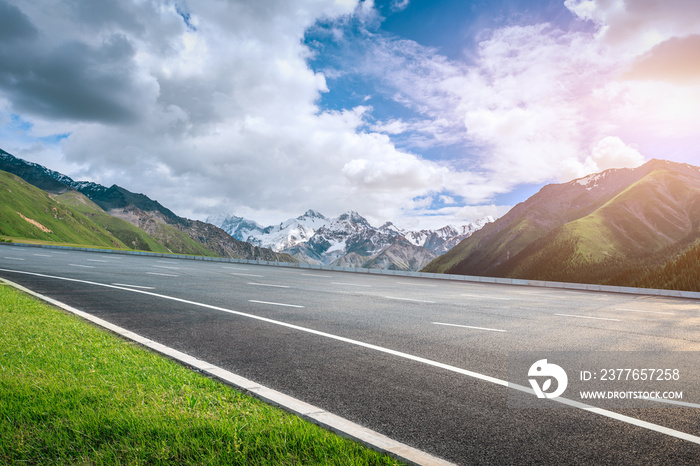 Asphalt road and snow mountain under blue sky. Highway and mountain background.