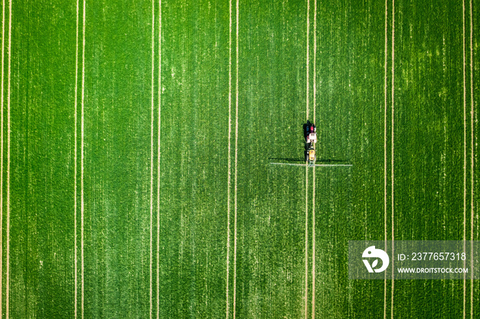 Small tractor spraying the chemicals on the field, aerial view