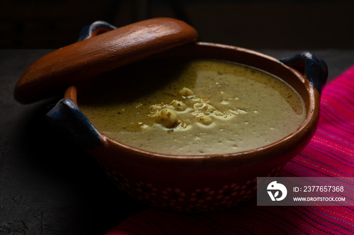 Mexican green pozole in cazuela on dark background