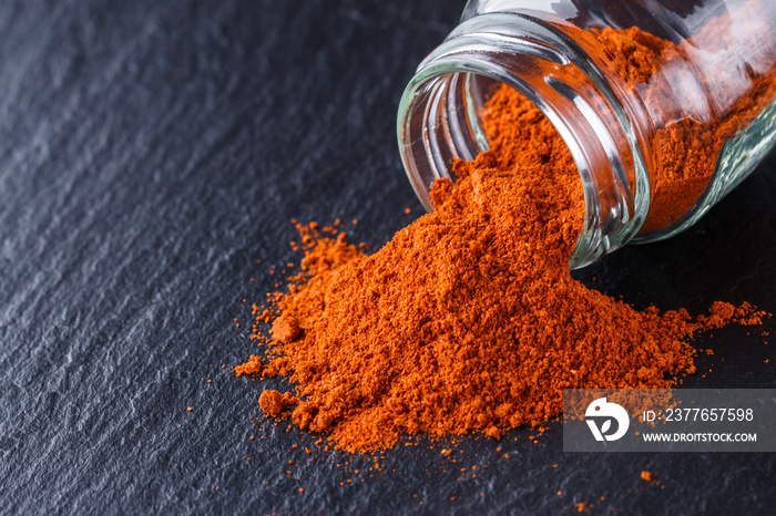 aromatic spicy chilli powder on a dark stone background