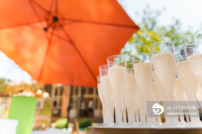 Many wine glasses with champagne. close up on the white table. Catering for business people and wedding ceremony. Welcome drink zone with champagne in disposable plastic wine cups.