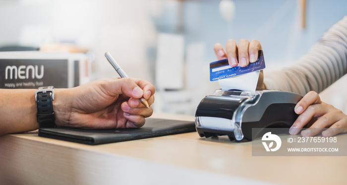 Customer using credit cart for payment to owner at cafe restaurant, cashless technology and credit card payment concept