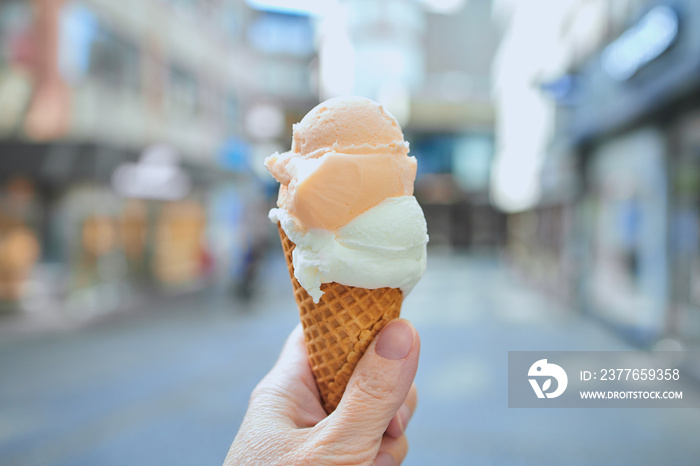 hand is holding ice cream cone in a city center