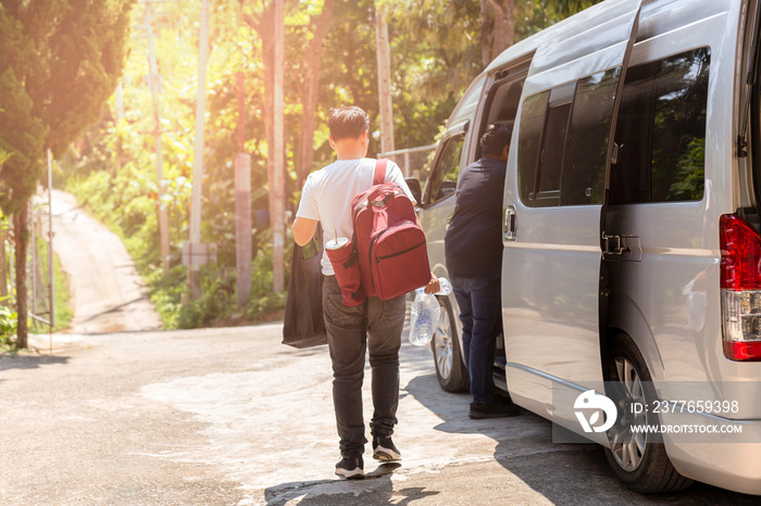 Passenger boarding on travel van with carry bag and bottle water.