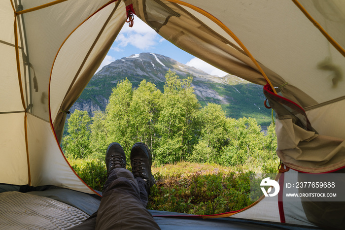 Guy is looking from the tent to the mountains